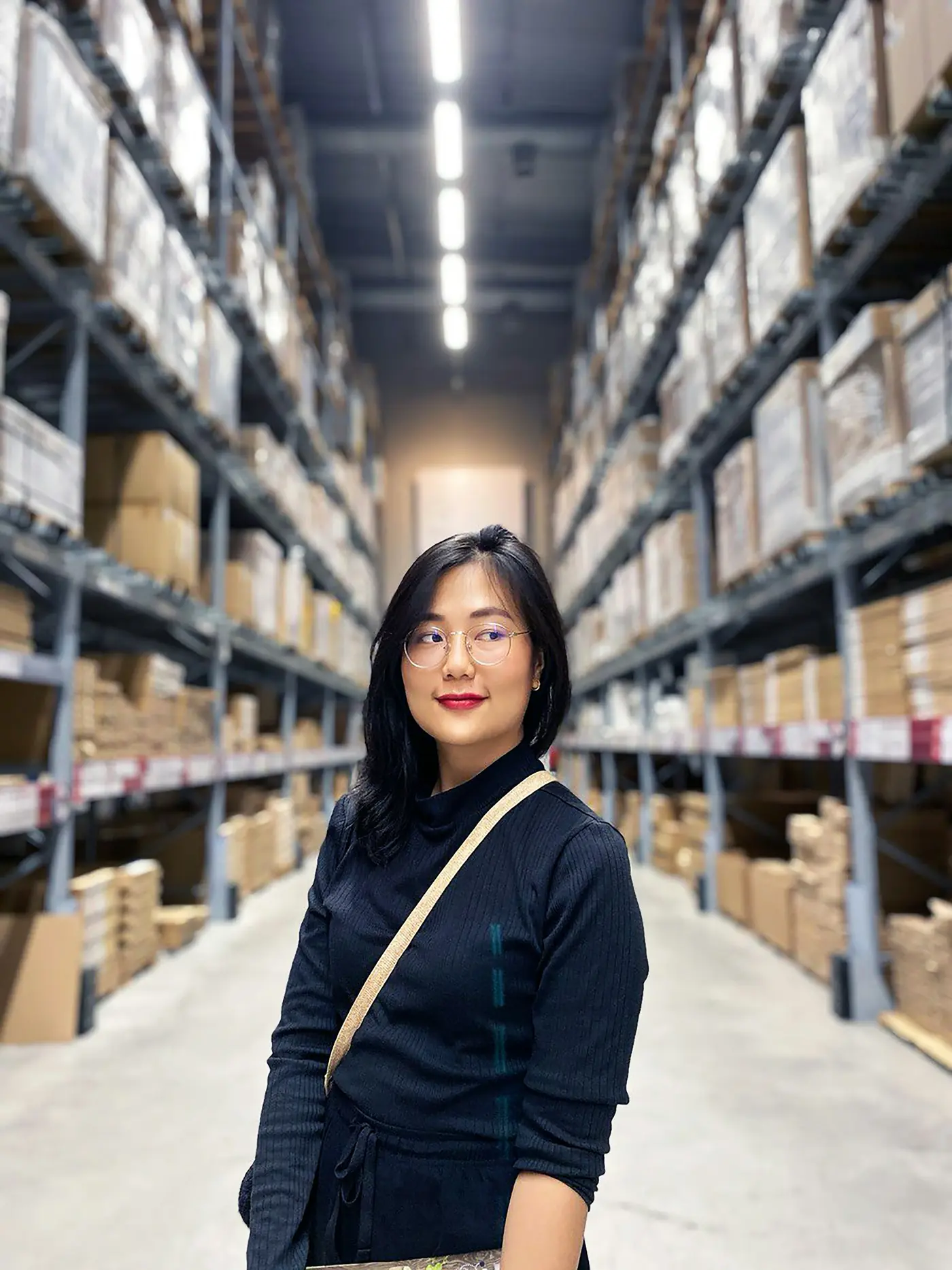 Logistics coordinator reviewing stock in a warehouse aisle.