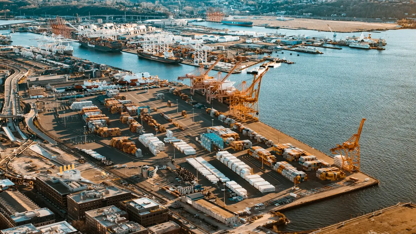 Aerial view of a working seaport with container terminals and berthed vessels.