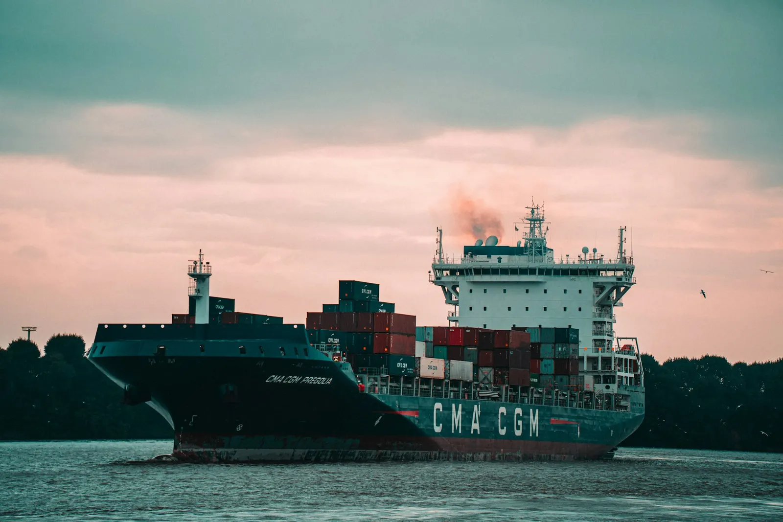 Cargo vessel moored at a port terminal at dusk.